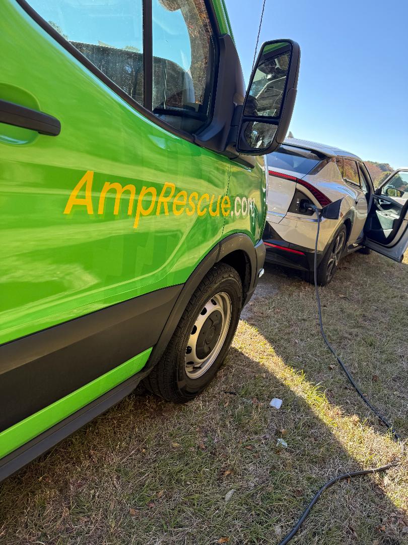 AMP Rescue van beside a parked electric vehicle with a charging cable connected